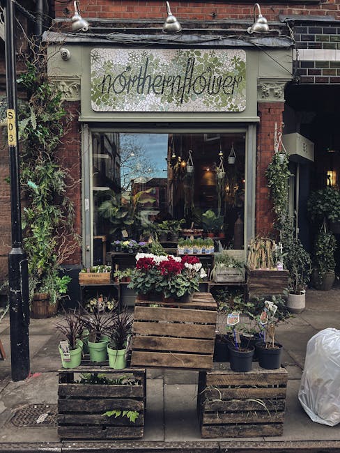 The exterior of Northern Flower, a florist shop on Fortis Green Road N2, features a brick building with a white sign displaying the business name in cursive lettering, surrounded by green floral illus